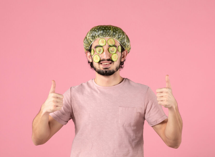 front-view-of-young-man-applying-cucumber-mask-on-his-face-on-pink-wall